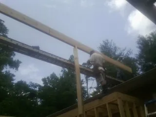 Carpenter setting a ridge beam over a new addition frame — Ice Dam Removal by Roofing Brothers in Ouaquaga