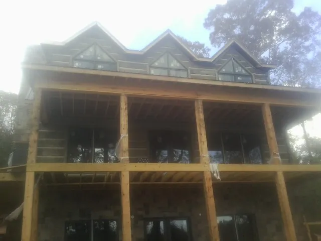 Dormers and porch framing on a large log home under construction — Roof Coating work by our crew in Ouaquaga