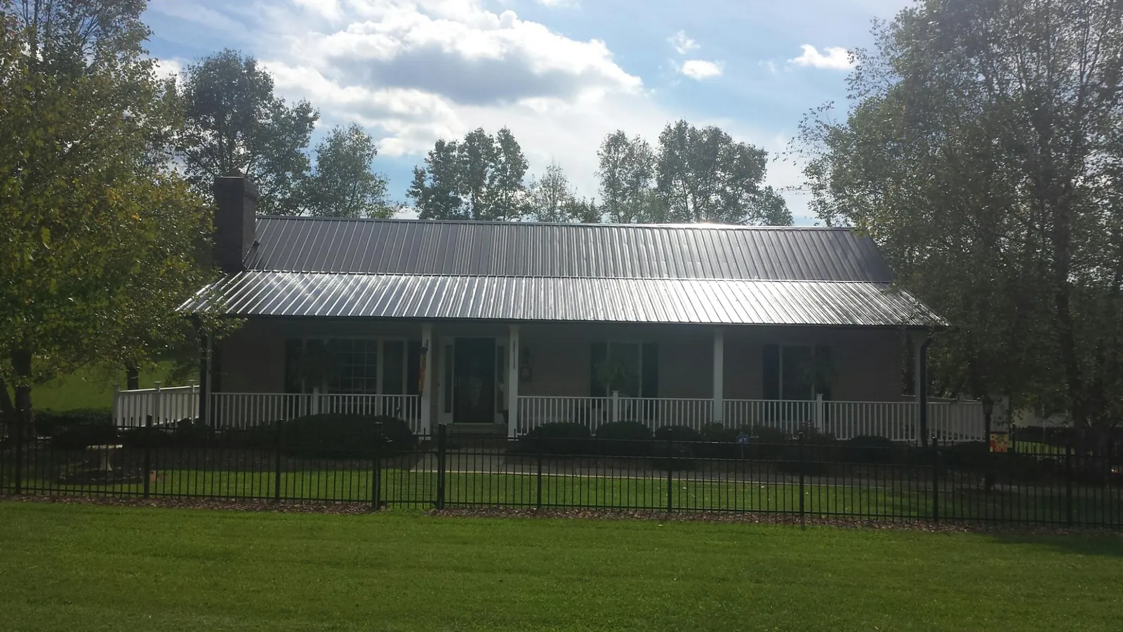 Gray metal roof on a brick ranch with a full width front porch — Gutter Guard Installation work by our crew in Ouaquaga