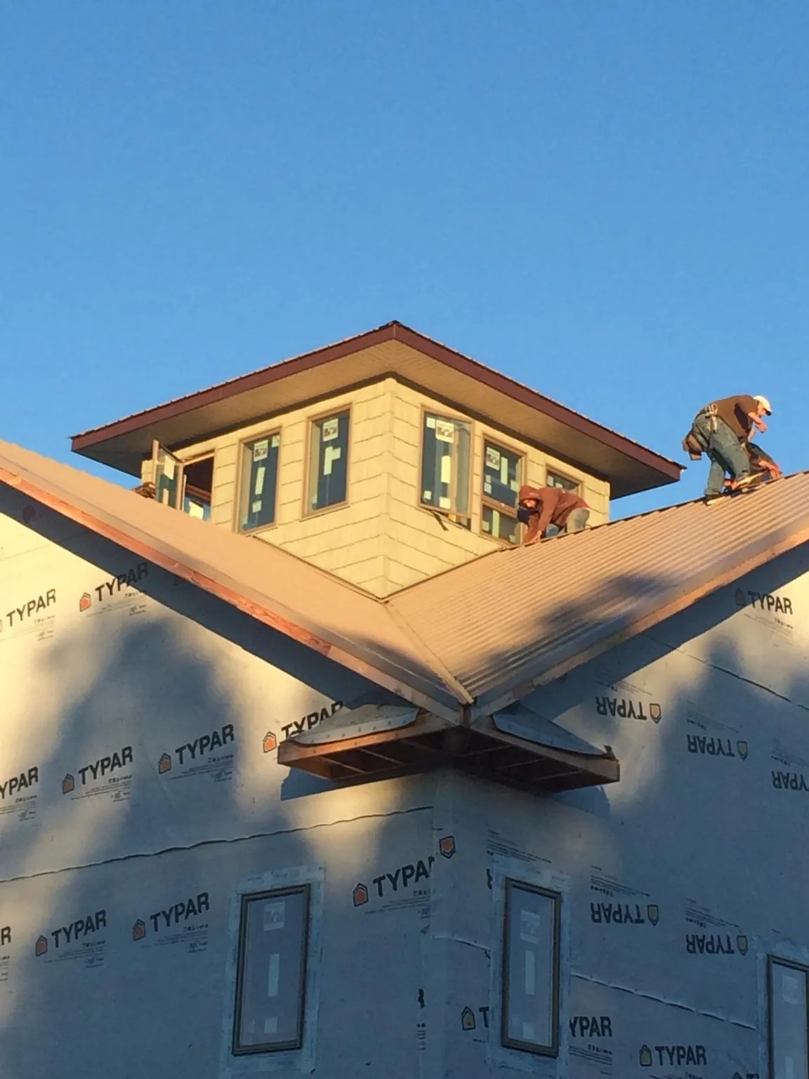 Roofers working around a rooftop cupola on a new metal roof at sunset — Roof Waterproofing in Ouaquaga by Roofing Brothers